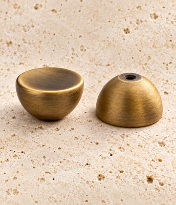 Antique Brass Dished Round Cabinet Knob on warm limestone