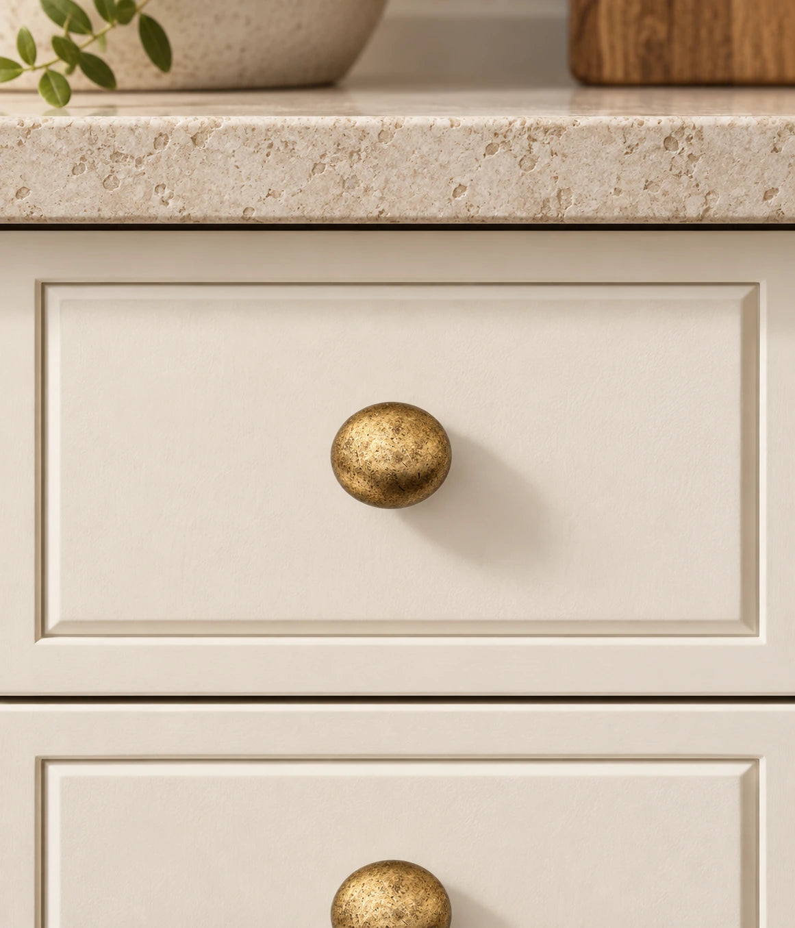 Antique Brass Distressed Round Cabinet Knobs installed on an ivory cabinet drawer