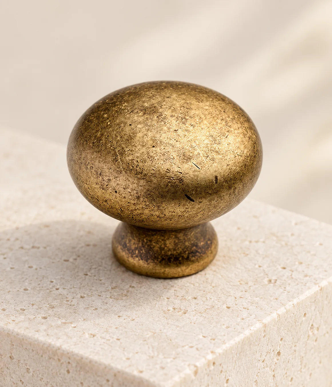 Close view of the domed face and mottled antique brass finish on a round cabinet knob