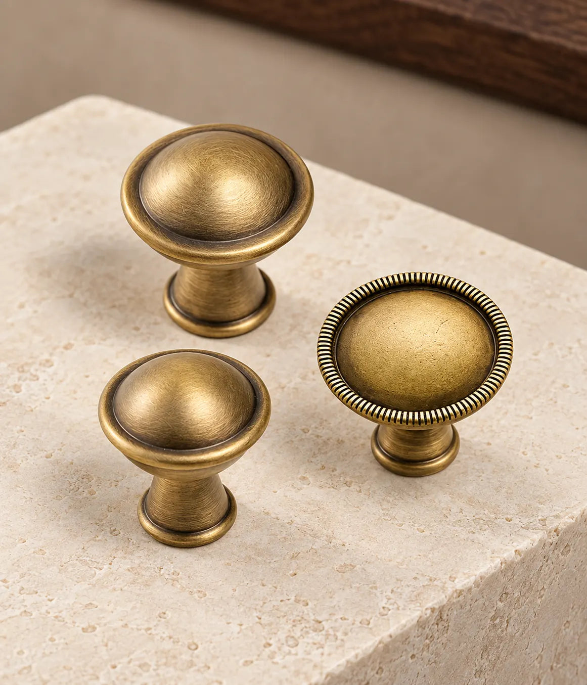 Antique brass domed cabinet knobs with ribbed and smooth rims arranged on pale limestone