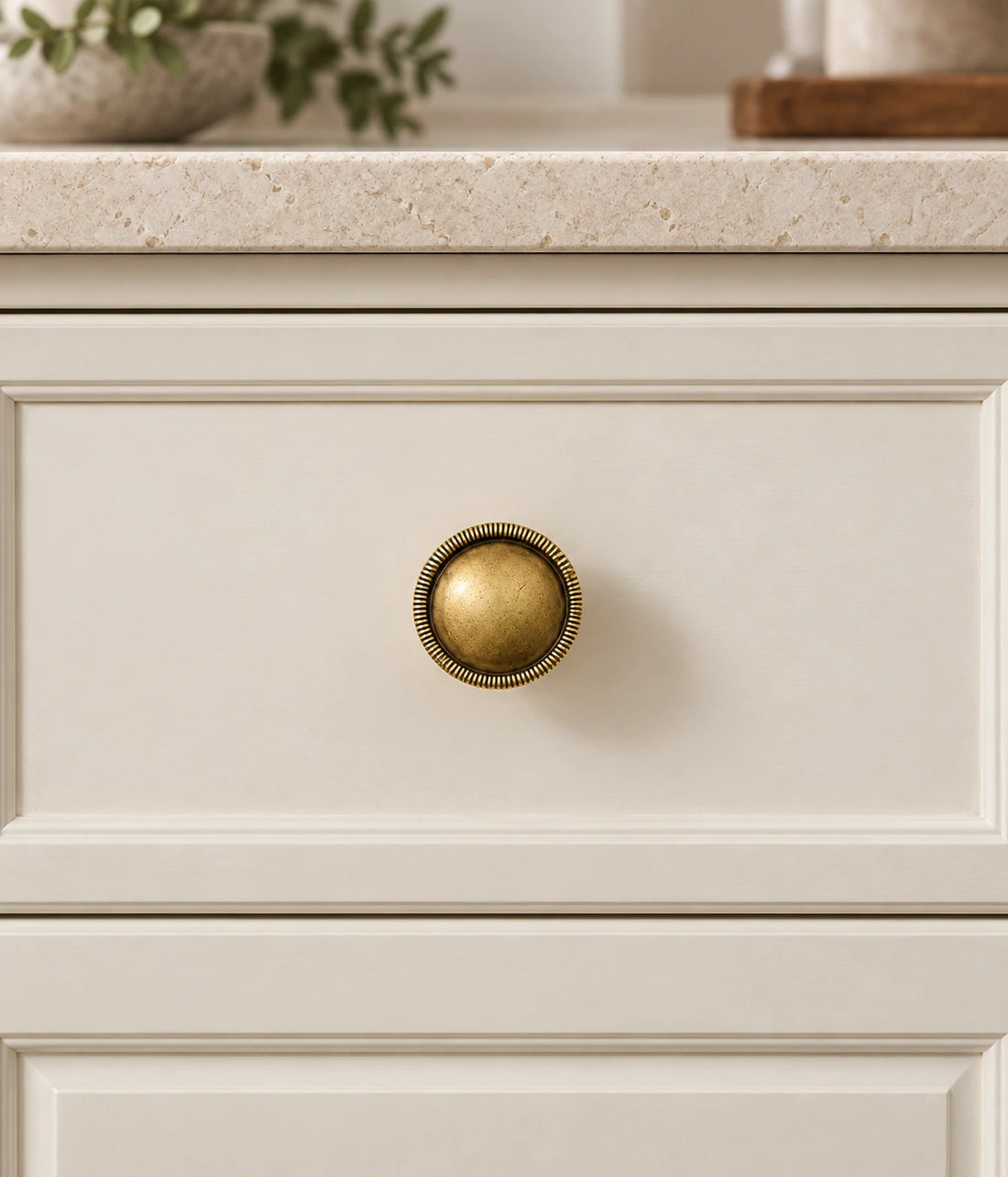 Antique brass domed cabinet knobs with ribbed and smooth rims arranged on pale limestone