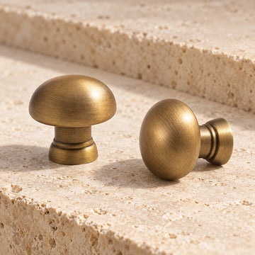 Antique brass domed mushroom cabinet knobs arranged on limestone
