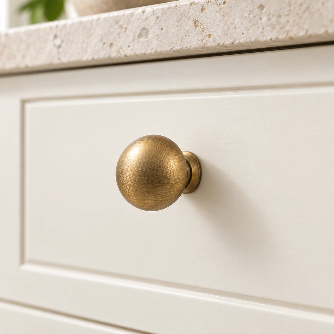 Antique brass domed mushroom cabinet knobs arranged on limestone