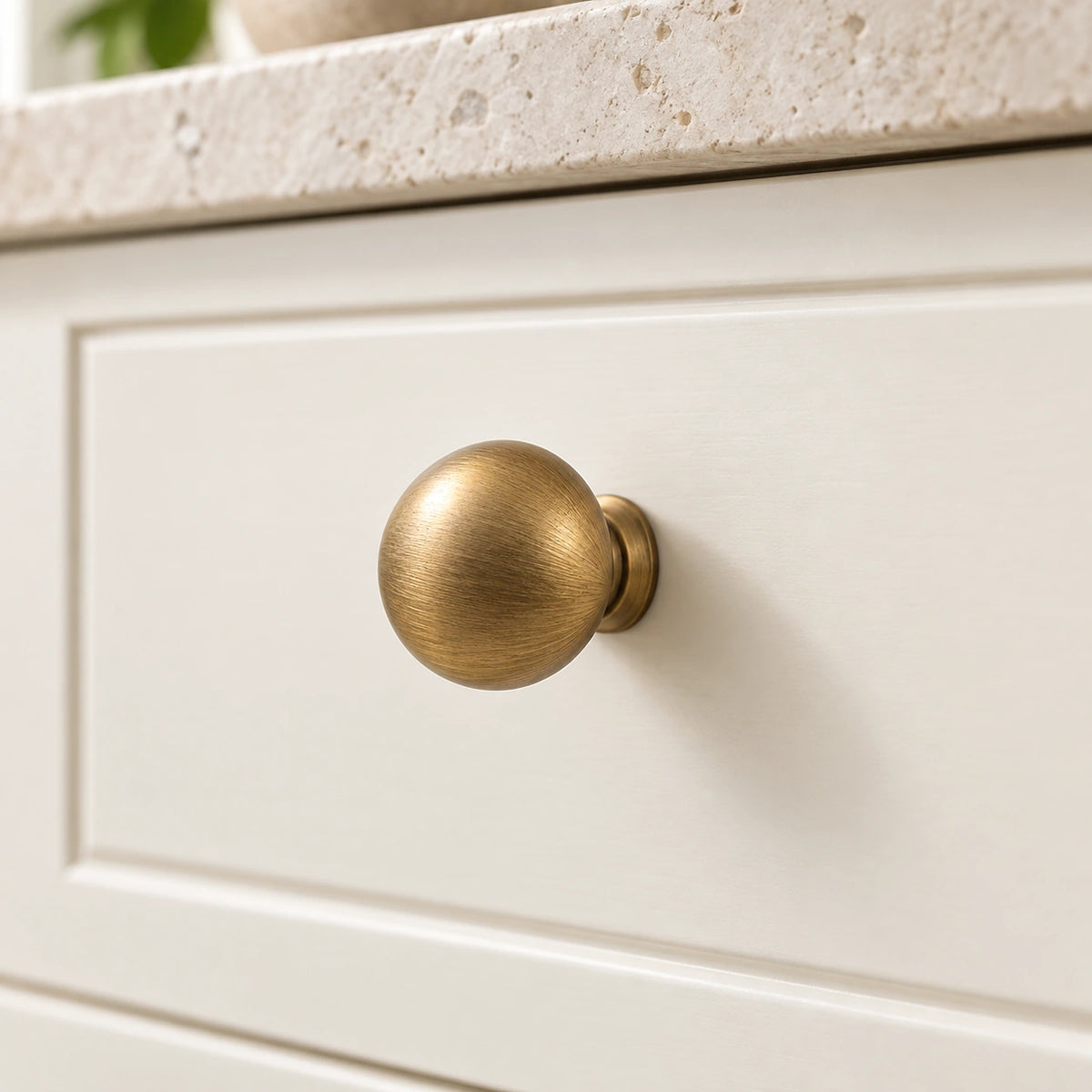 Antique brass mushroom cabinet knob mounted on an ivory drawer