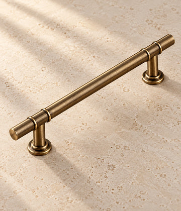 Antique Brass Double Collar Cabinet Pulls & T-Knob on warm limestone