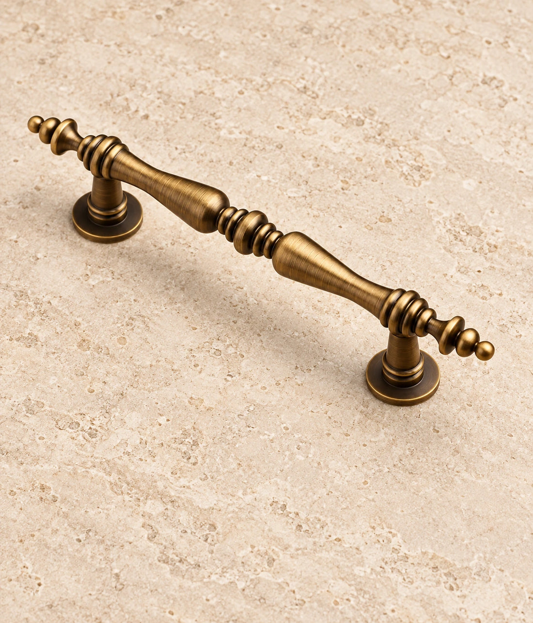Antique Brass Double-Spindle Finial Cabinet Pulls on warm limestone