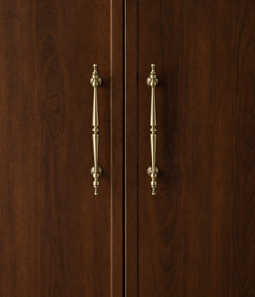 Antique brass double-spindle cabinet pulls installed vertically on dark wood doors
