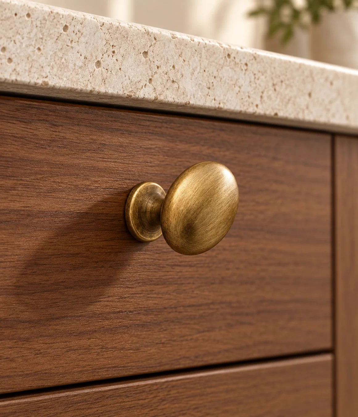 Smooth antique brass egg cabinet knob installed on a walnut drawer