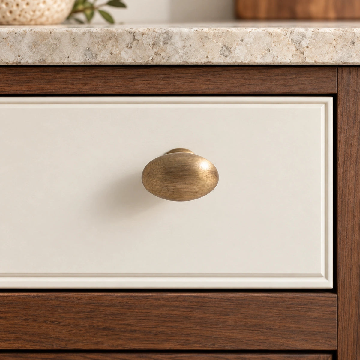 Antique Brass Egg Cabinet Knob installed on an ivory cabinet drawer front