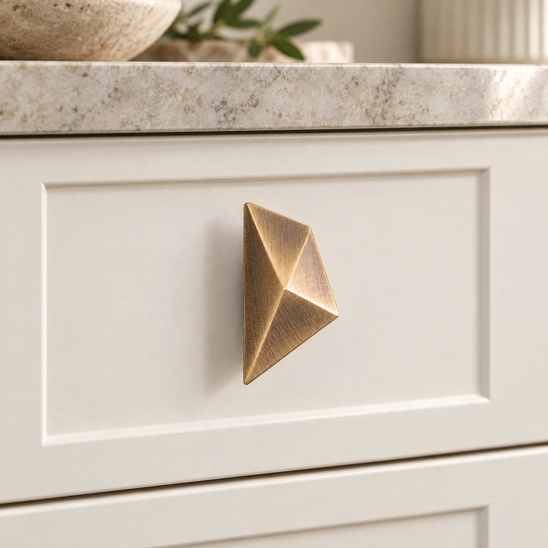 Antique brass faceted geometric cabinet knobs on limestone