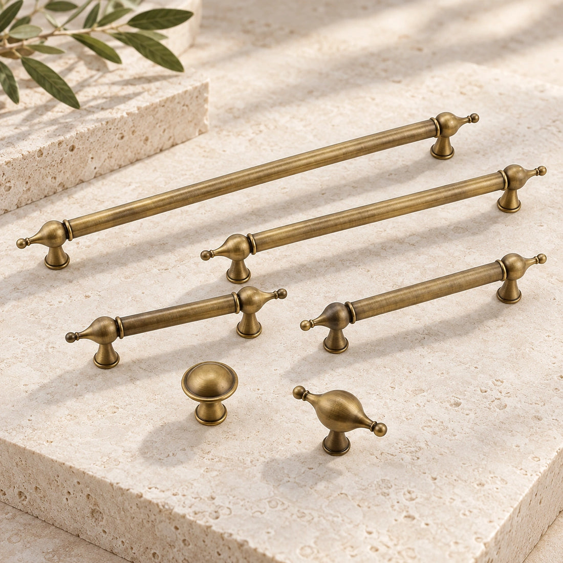 Antique brass finial cabinet pulls, round knob and T-knob arranged on limestone