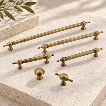 Antique brass finial cabinet pulls, round knob and T-knob arranged on limestone