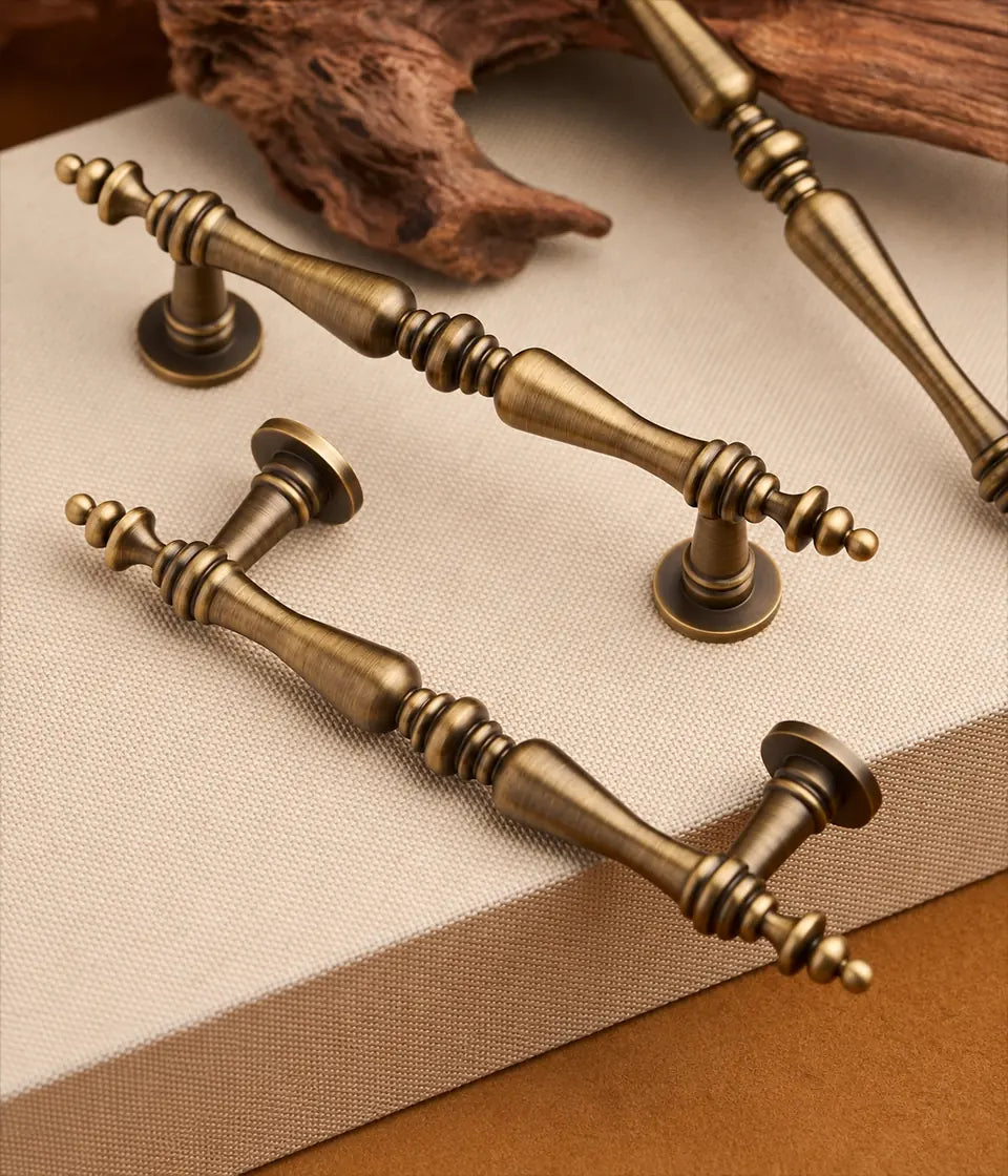 Antique brass double-spindle cabinet pulls with decorative finials arranged on linen