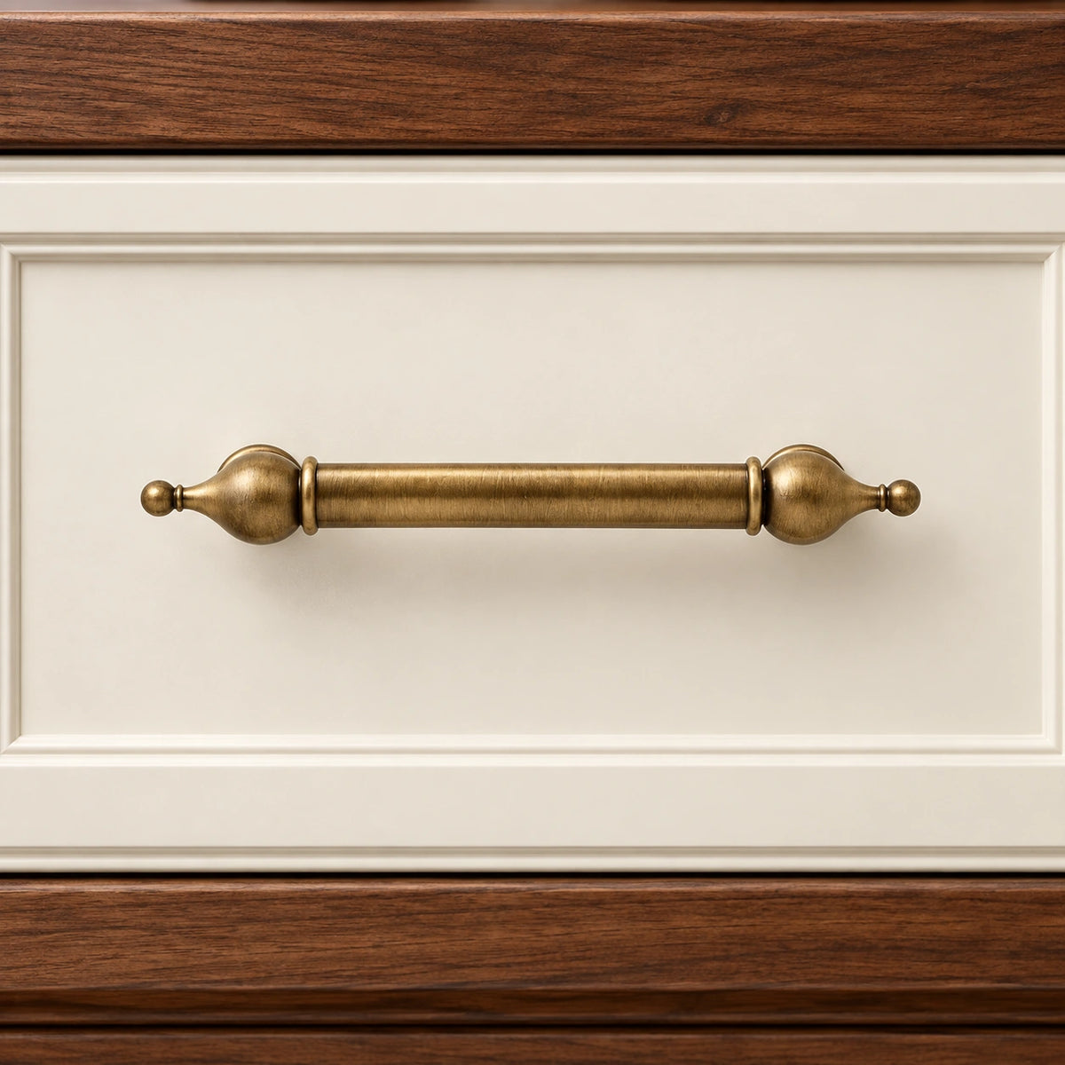 Antique brass finial bar pull mounted on an ivory drawer