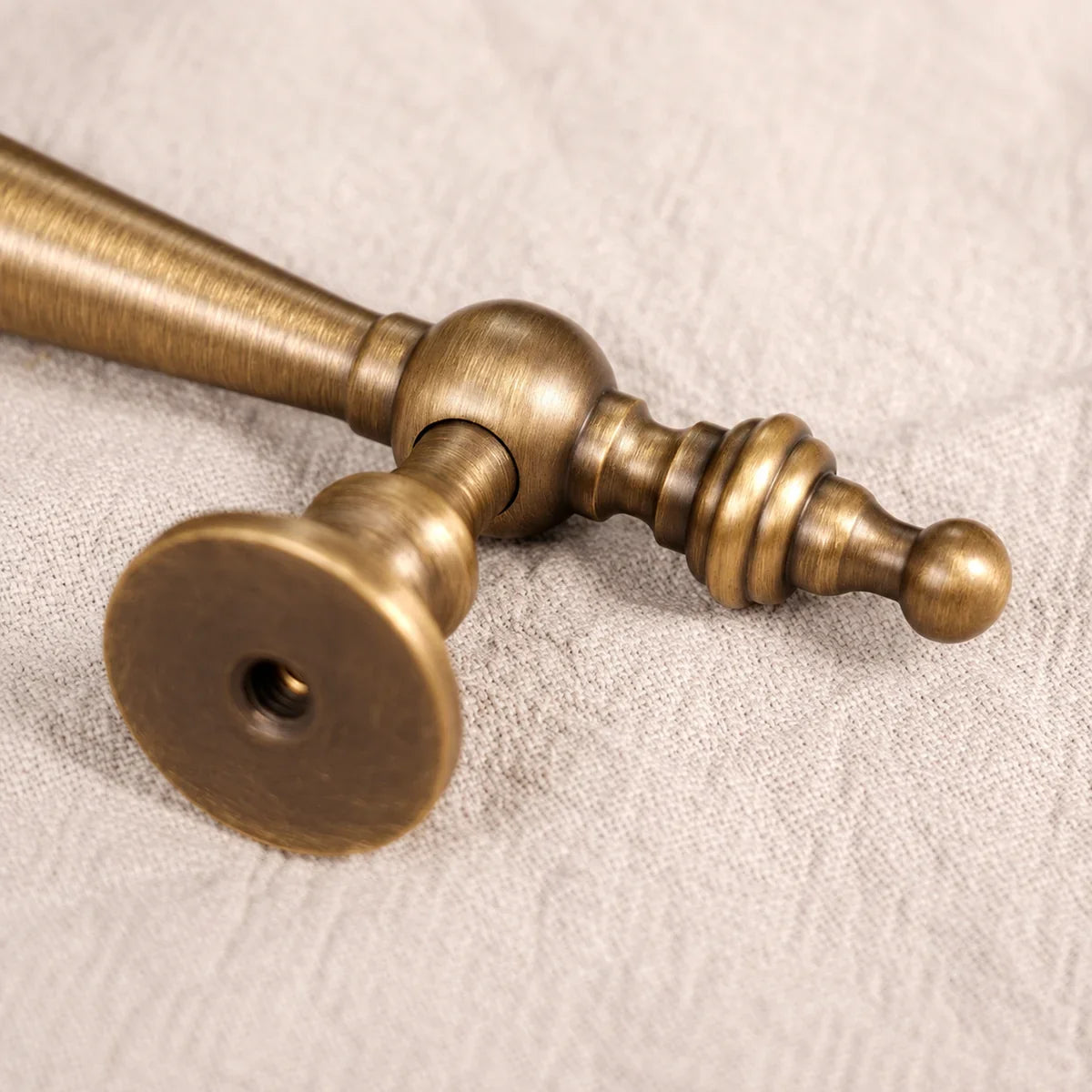 Rear mounting hole and turned finial detail on a brass cabinet pull