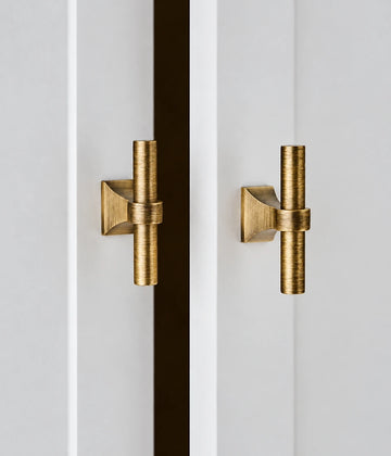 Antique brass T-knobs with flared bases fitted to light cabinet doors