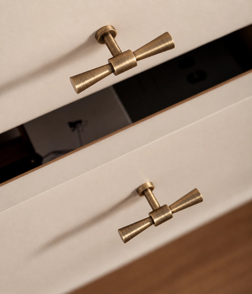 Flared antique brass T-knobs installed on cream drawers