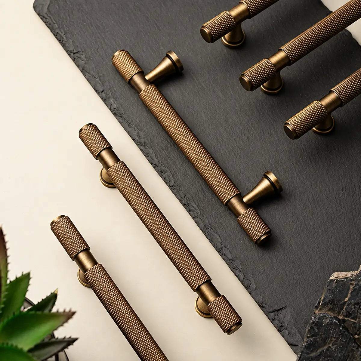 Antique brass flared-post knurled cabinet pulls arranged on slate and a light surface