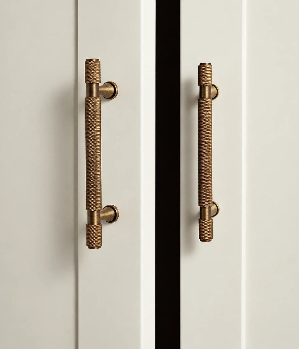 Antique brass knurled cabinet pulls with flared posts on cream cabinet doors