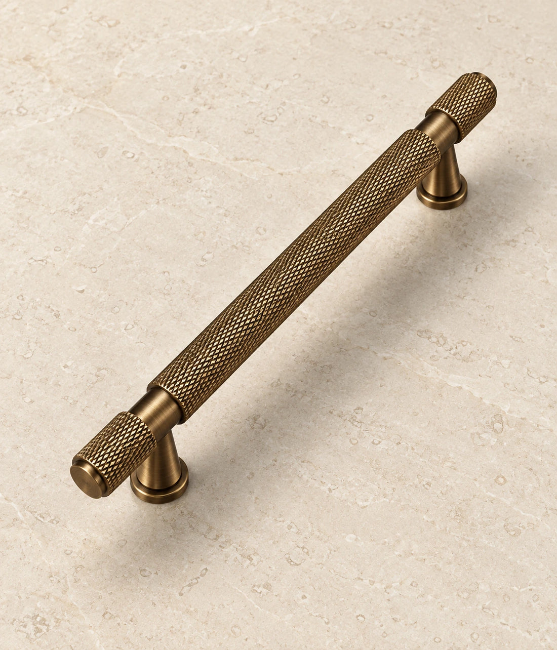 Antique Brass Flared-Post Knurled Cabinet Pulls on warm ivory limestone