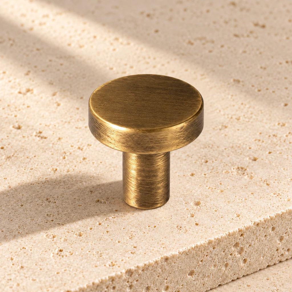 antique brass flat disk knob limestone on pale limestone.