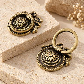 Antique brass floral bow ring pulls arranged on natural limestone