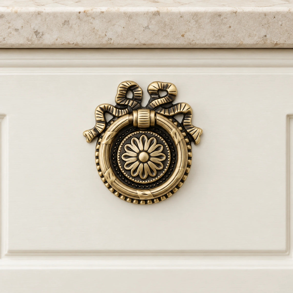 Antique brass floral ring pull mounted flush on an ivory drawer