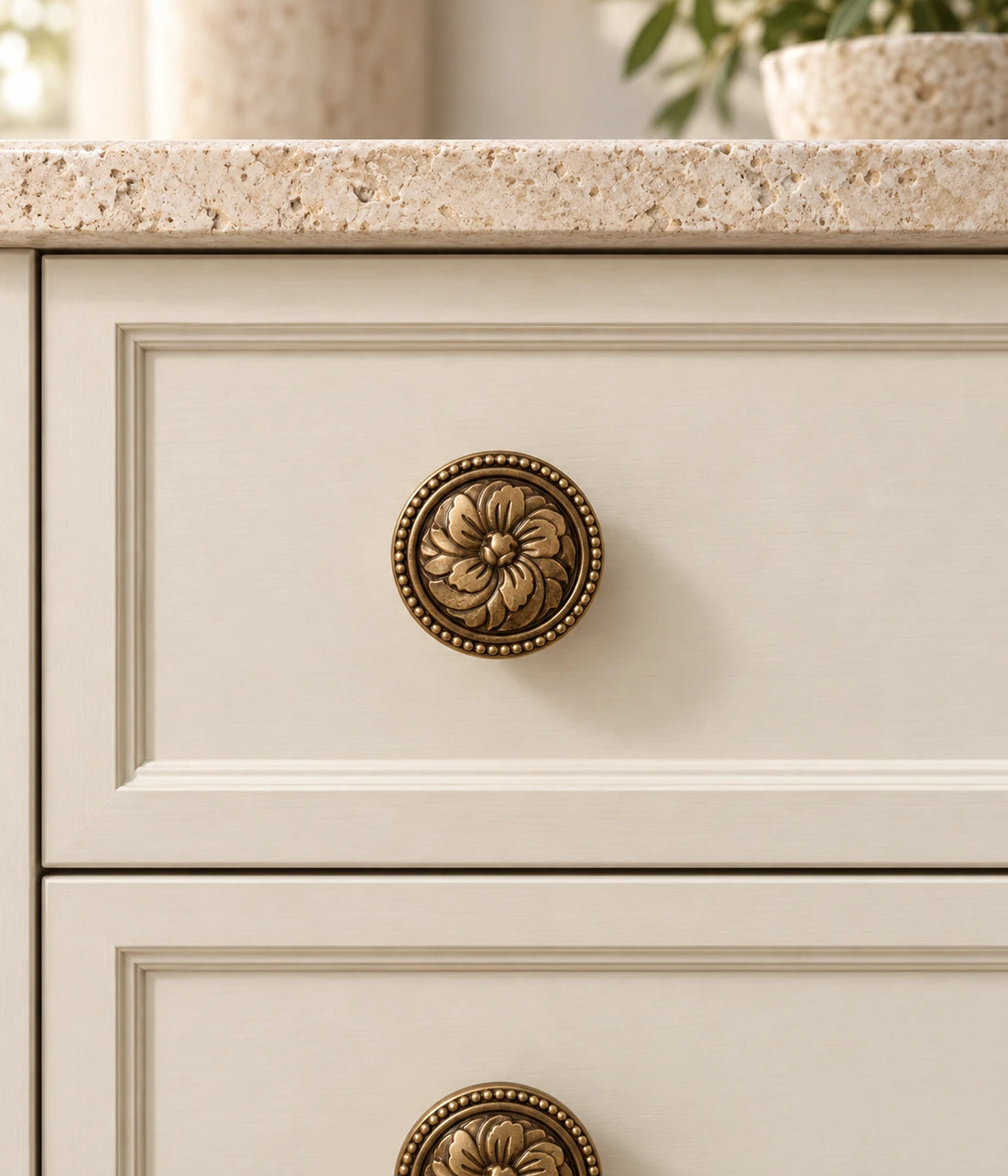 Antique brass floral rosette cabinet knob with beaded rim on warm limestone