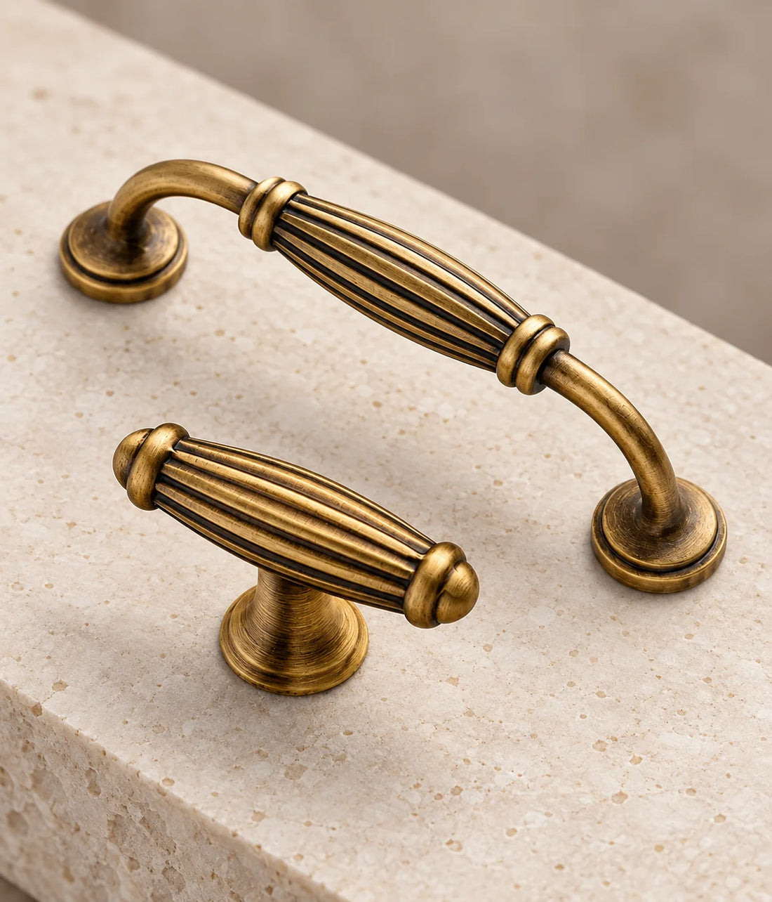 Antique brass fluted barrel cabinet pulls and T-knob arranged on limestone
