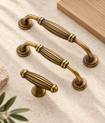 Antique brass fluted barrel cabinet pulls and T-knob arranged on limestone