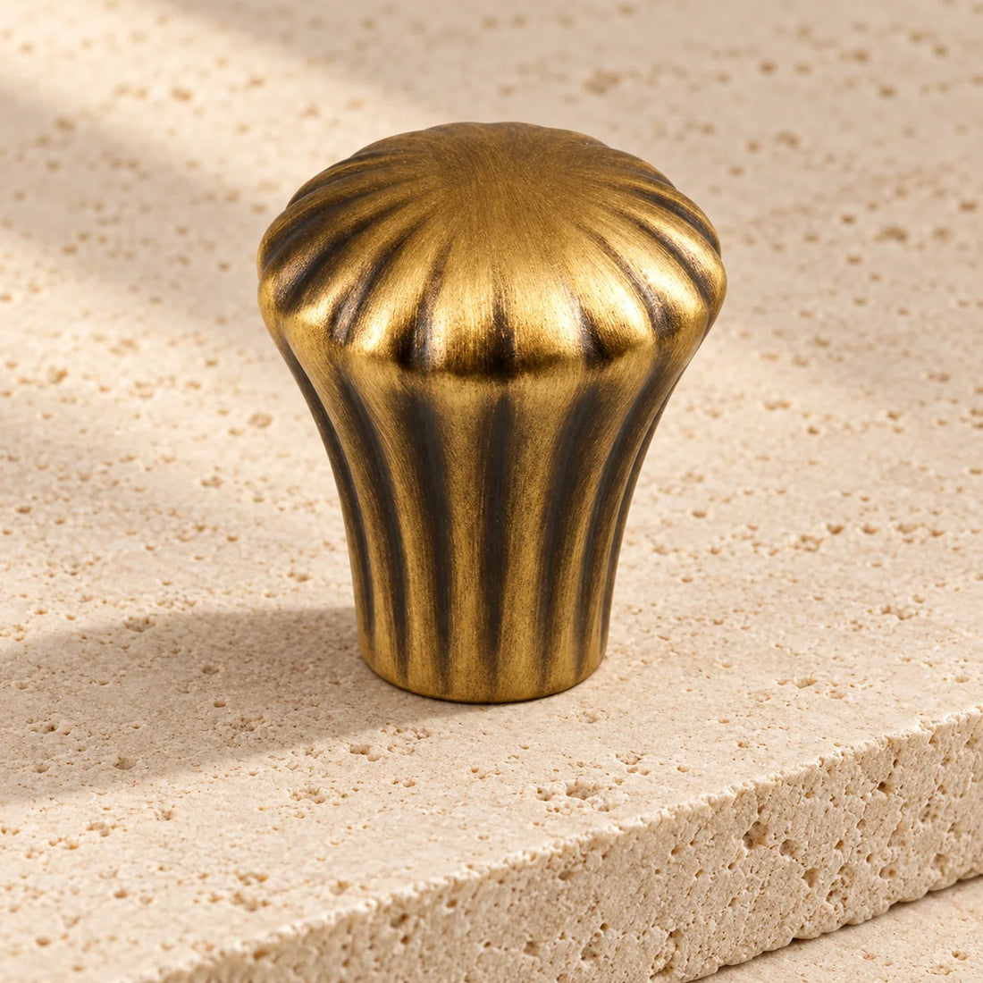 antique brass fluted cabinet knob on pale limestone.