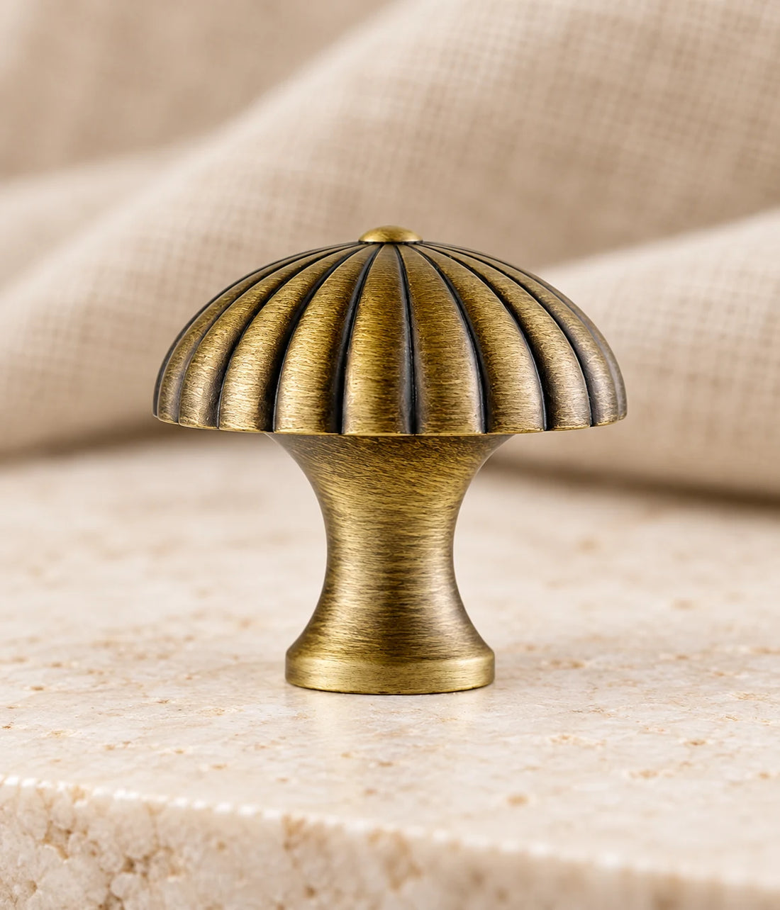 Antique brass fluted canopy cabinet knobs on pale limestone with walnut and warm neutral background