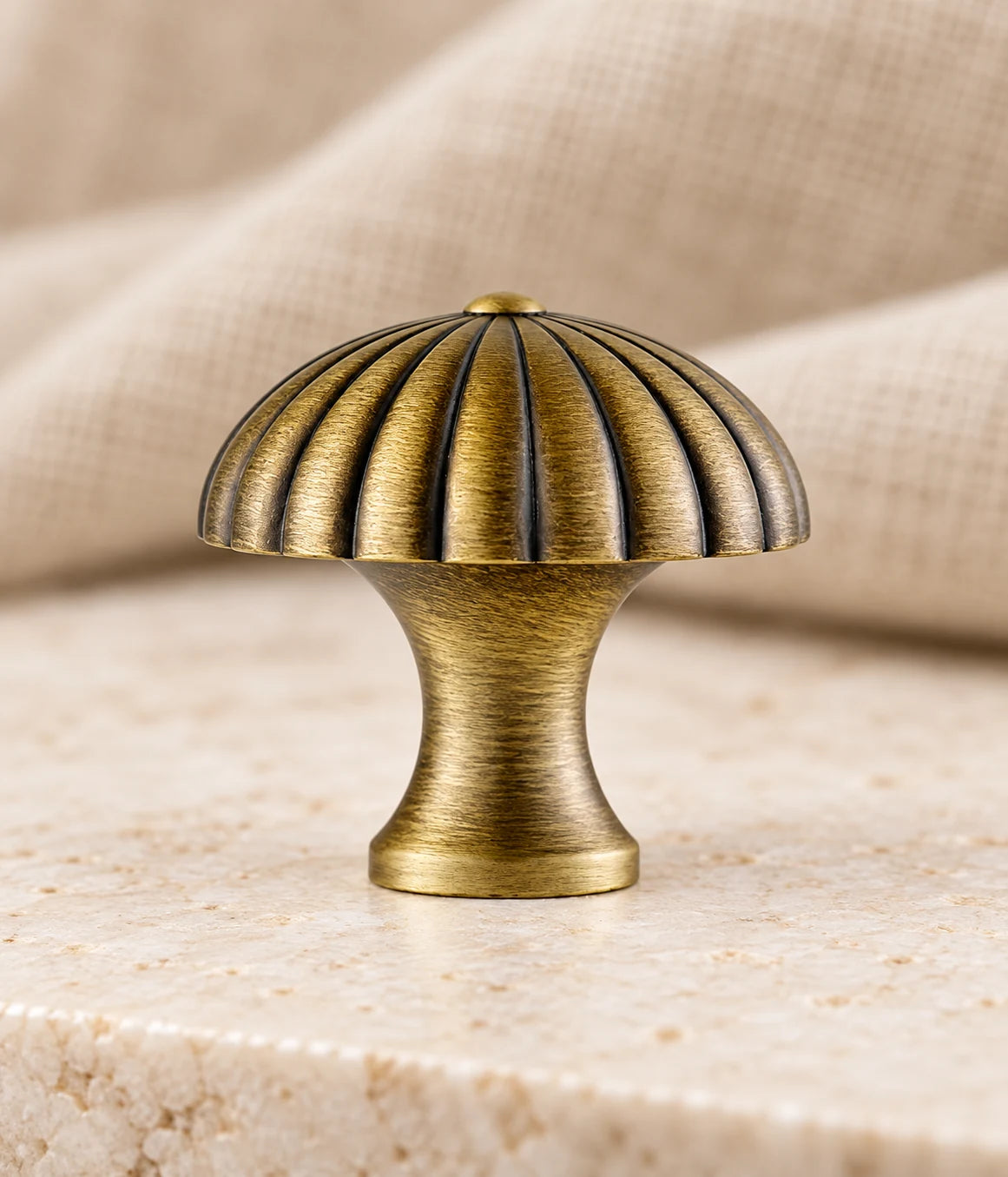 Close-up of fluted dome and smooth waisted stem on antique brass cabinet knob