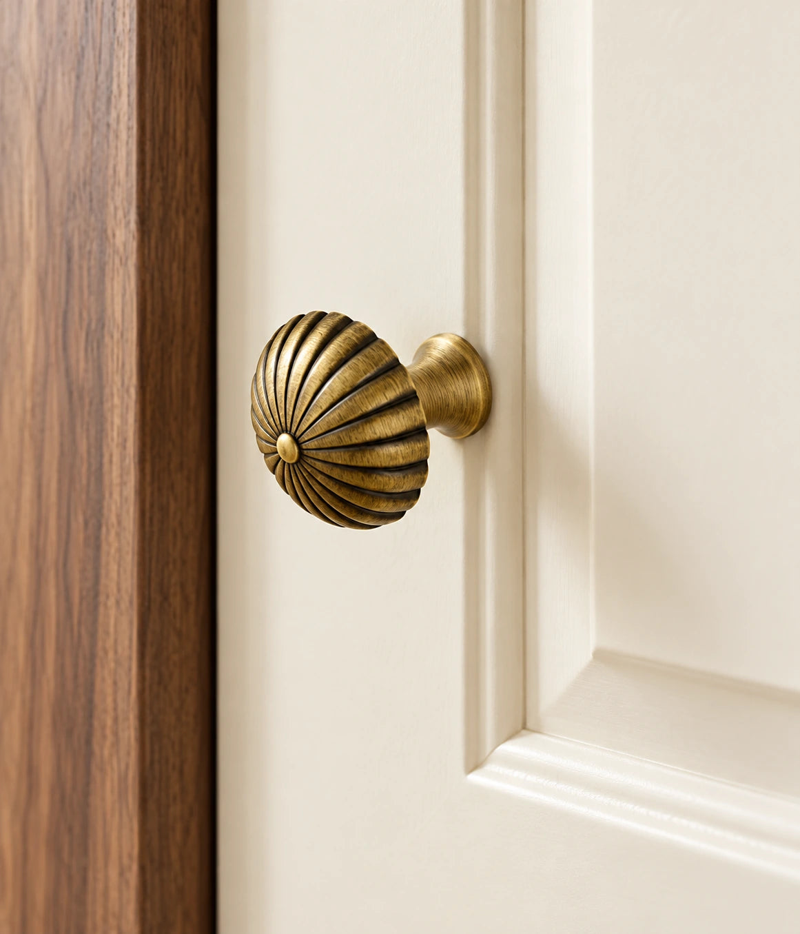 Antique brass fluted canopy knob fitted to a warm ivory cabinet door