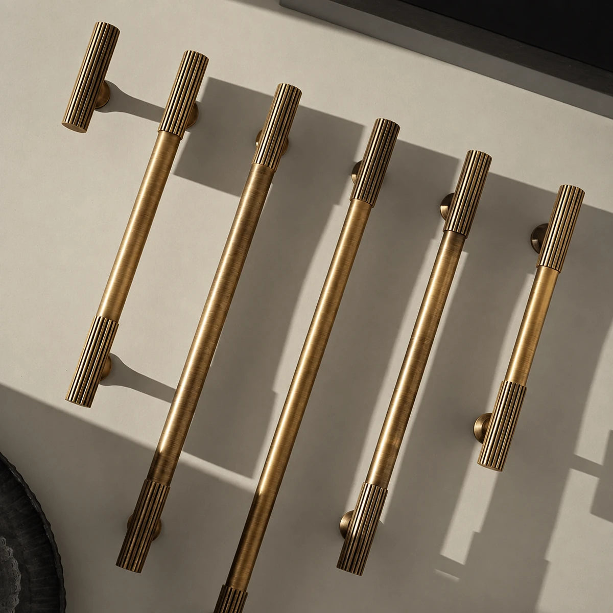 Antique brass fluted end pulls and T-knob arranged in directional light