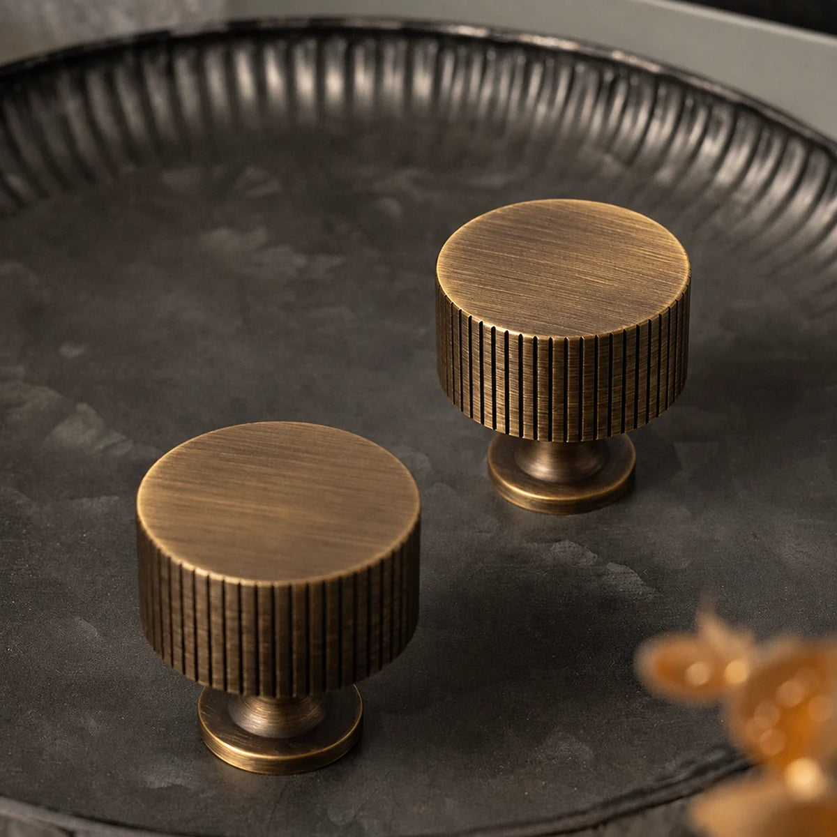 Two antique brass fluted drum knobs showing the brushed tops and grooved edges