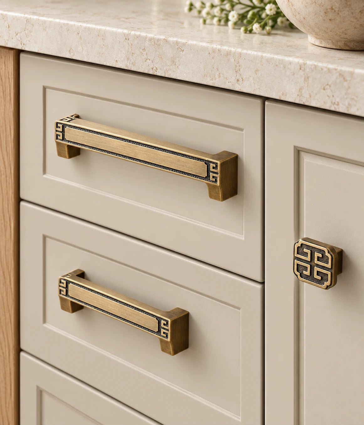 Antique brass geometric pulls and square knob installed on cream cabinetry