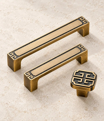 Antique brushed brass geometric cabinet pulls and square knob arranged on limestone