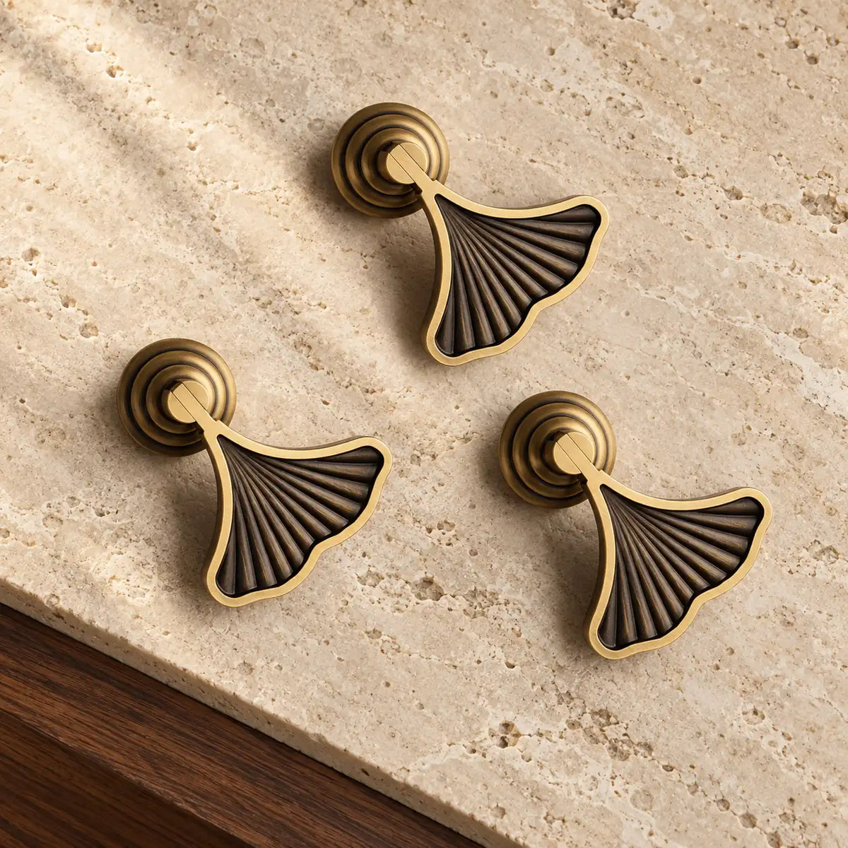 Antique brass ginkgo fan pendant cabinet pulls on warm limestone