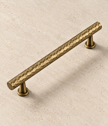 Antique Brass Hammered Cabinet Pulls & Knobs on warm limestone