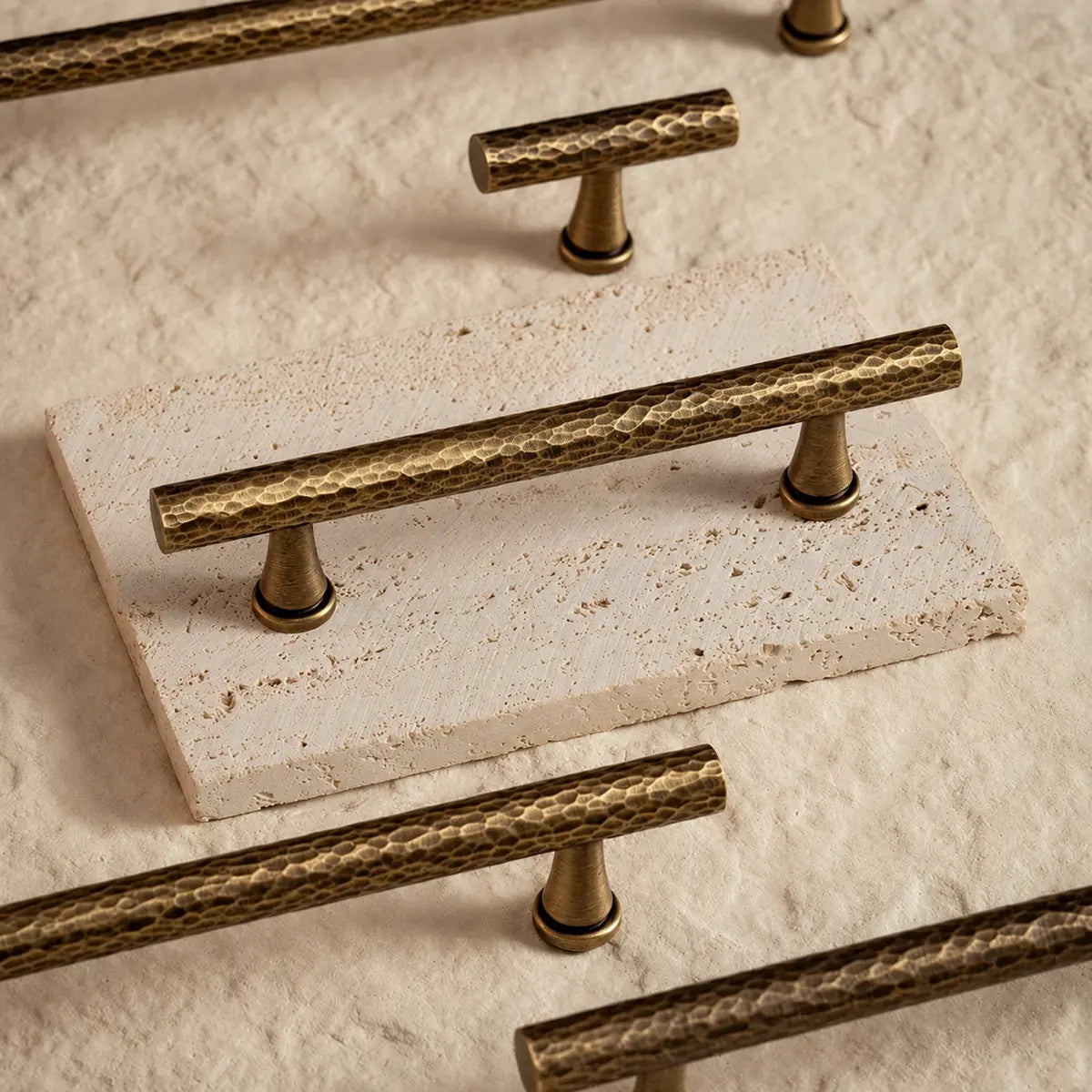 Hammered antique brass cabinet pulls and T-knob on pale stone