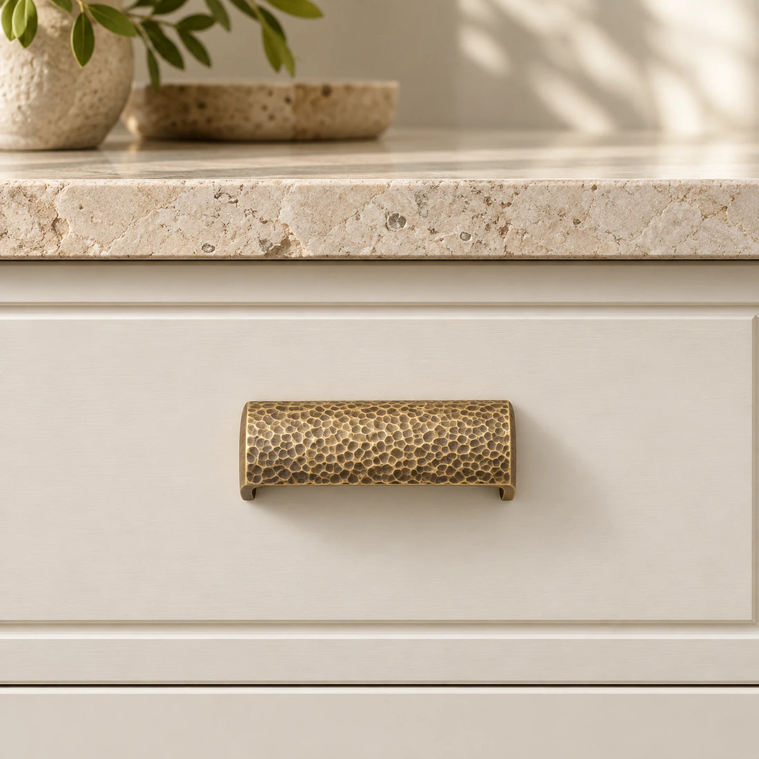 Antique brass hammered semicircle cabinet pulls on ivory limestone