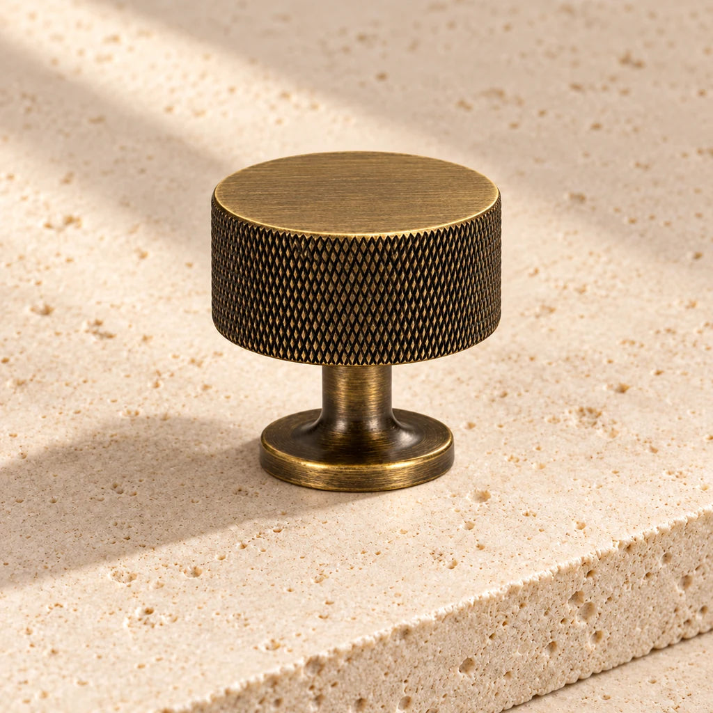 antique brass knurled round knob on pale limestone.