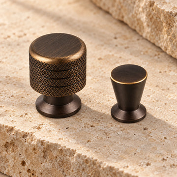 Antique brass knurled and tapered cabinet knobs arranged on limestone