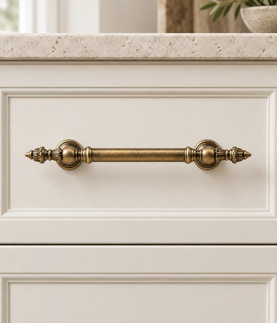 Three antique brass leaf-finial cabinet pulls arranged on pale limestone