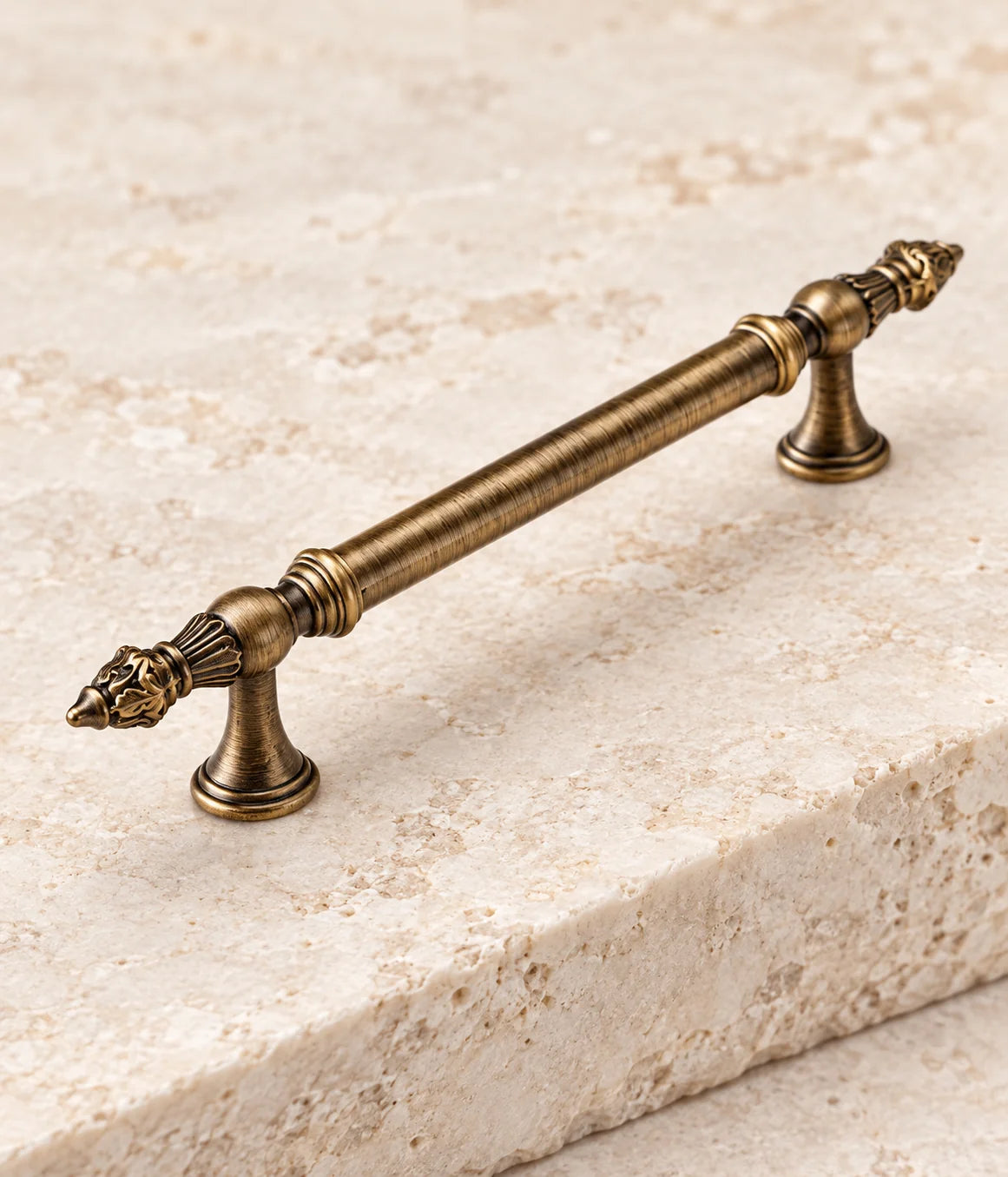 Detailed carved leaf finial and flared mounting post on an antique brass cabinet pull