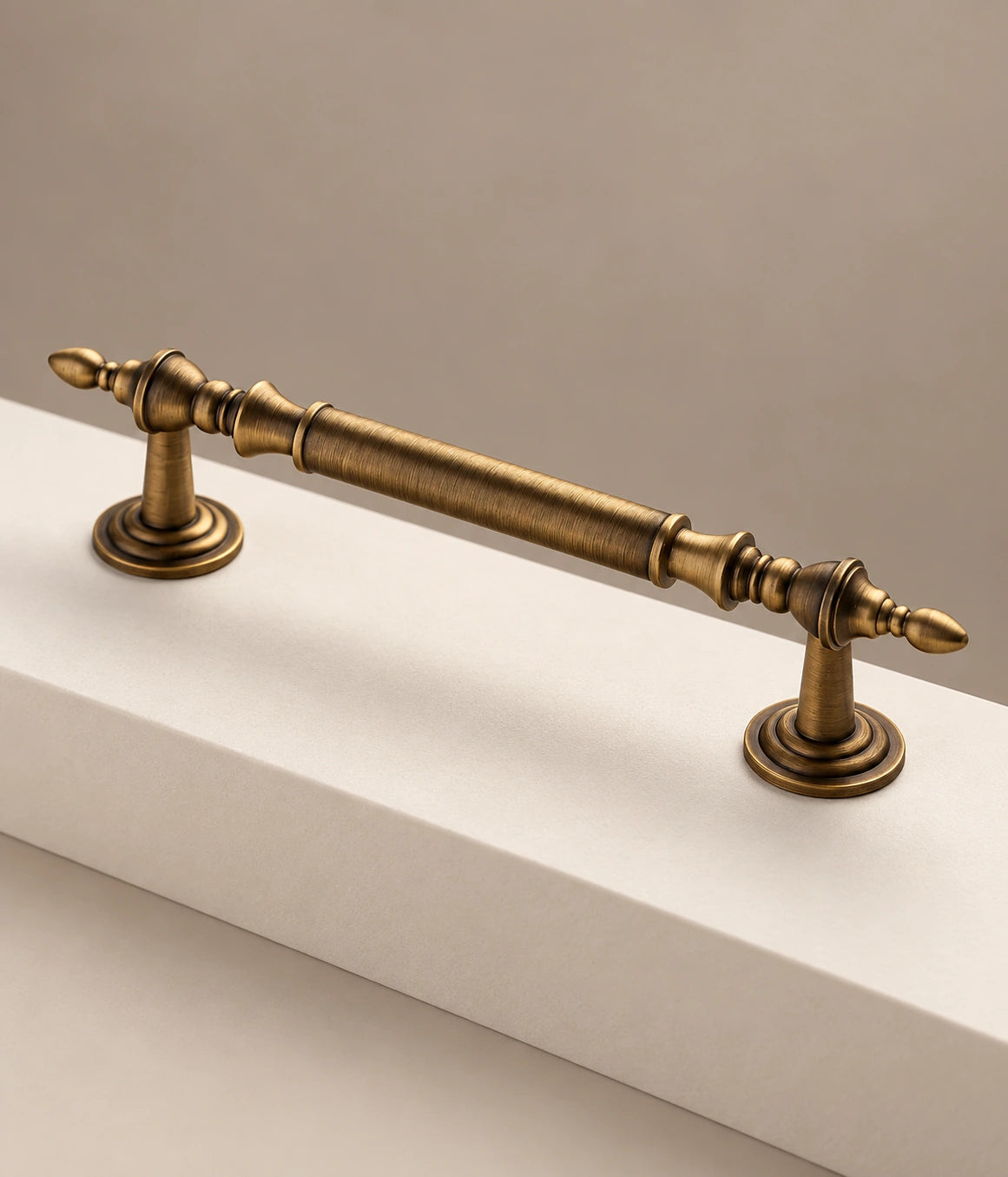 Turned collars, pointed leaf tips and stepped circular feet on an antique brass cabinet pull