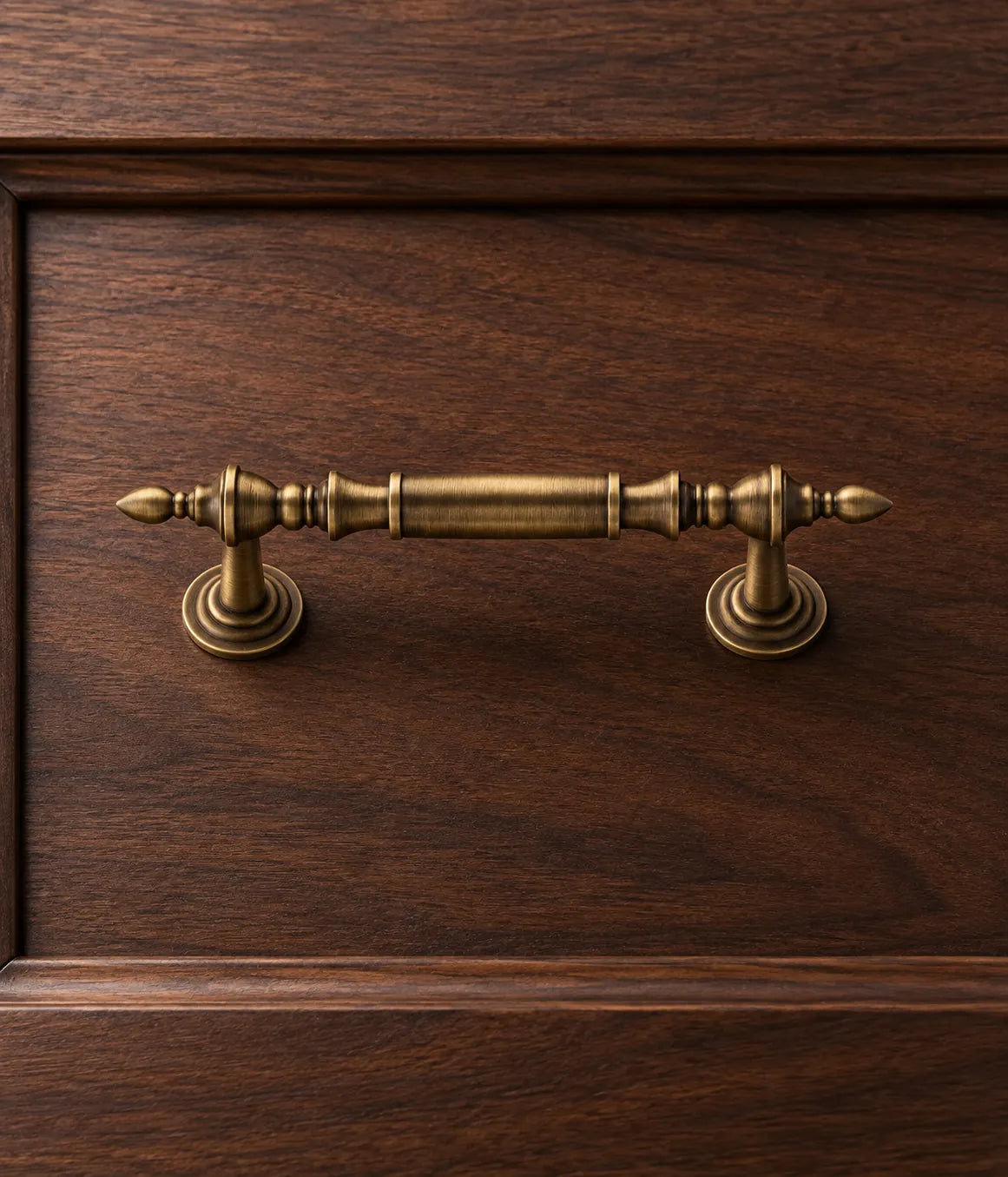 Antique brass leaf-tip pull mounted on a dark walnut drawer