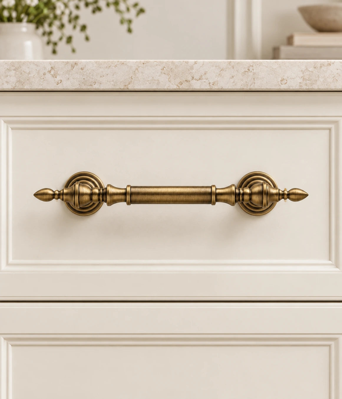 Antique Brass Leaf-Tip Turned Cabinet Pulls installed on an ivory cabinet drawer