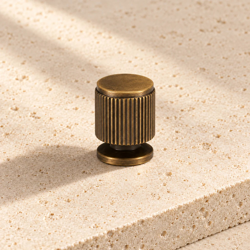 antique brass linear ridged knob on pale limestone.